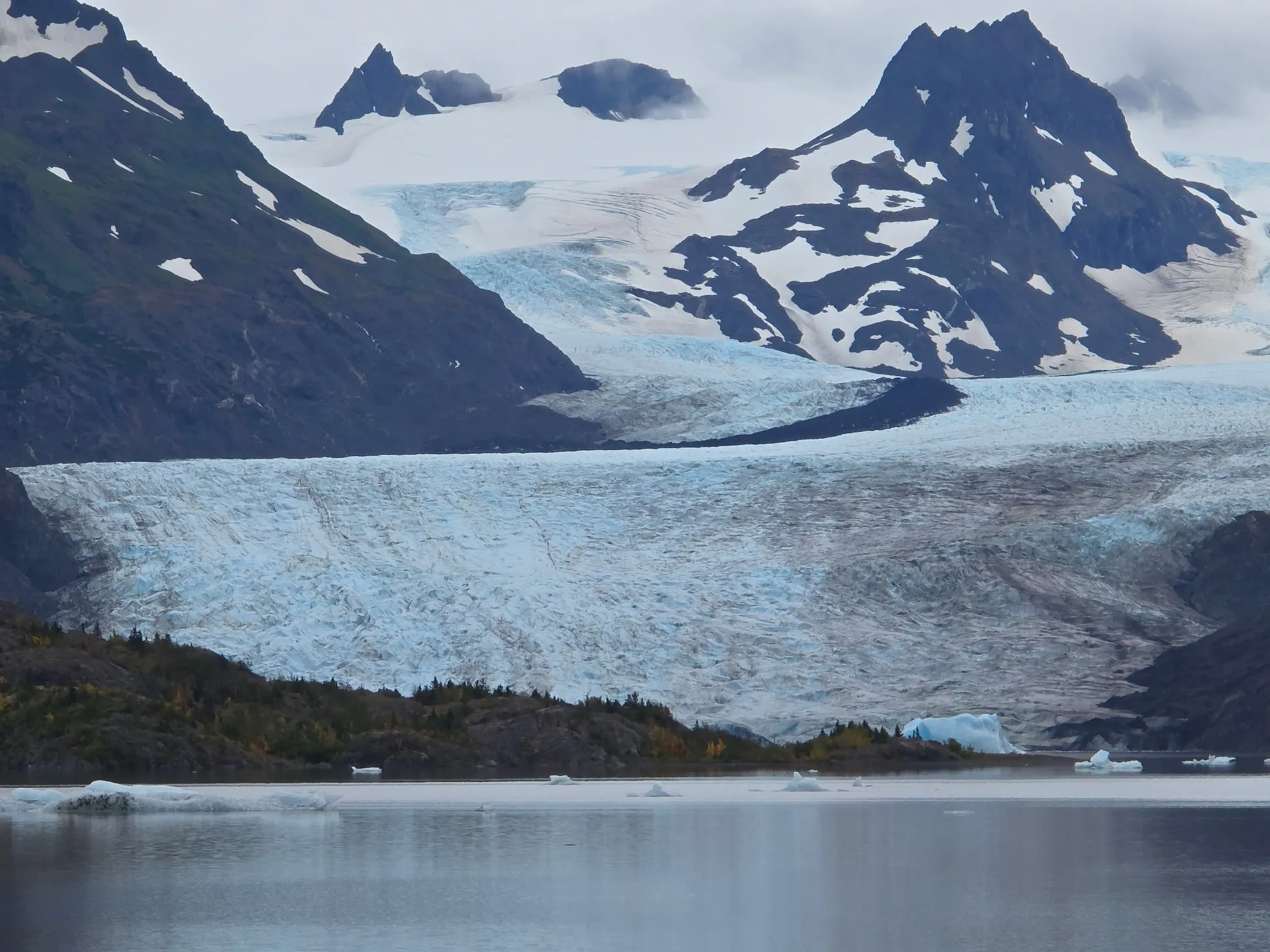 A tidewater glacier calving ice into a gray lagoon